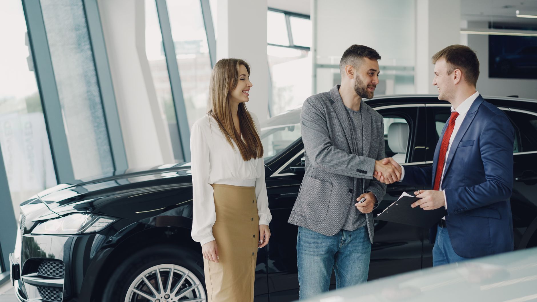 Klient podaje rękę doradcy w salonie przy podpisywaniu umowy na auto