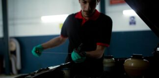 Mechanik sprawdza poziom oleju miarką w komorze silnika w warsztacie
