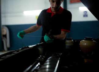 Mechanik sprawdza poziom oleju miarką w komorze silnika w warsztacie