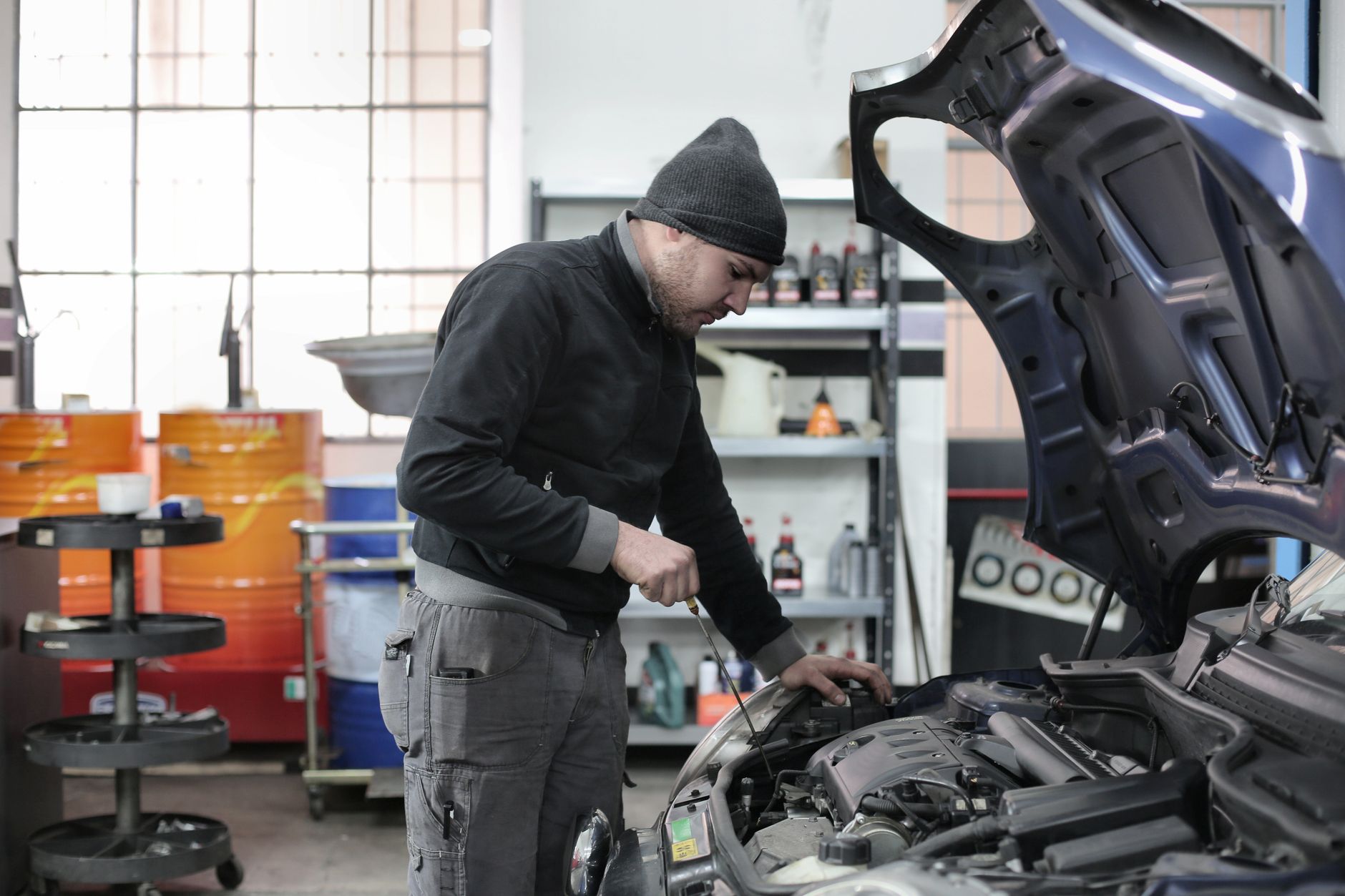 Mechanik w garażu sprawdza silnik auta podczas przeglądu płynów