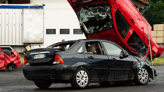 Czerwone auto po dachowaniu na czarnym samochodzie podczas kraksy Czerwone auto po dachowaniu na czarnym samochodzie podczas kraksy