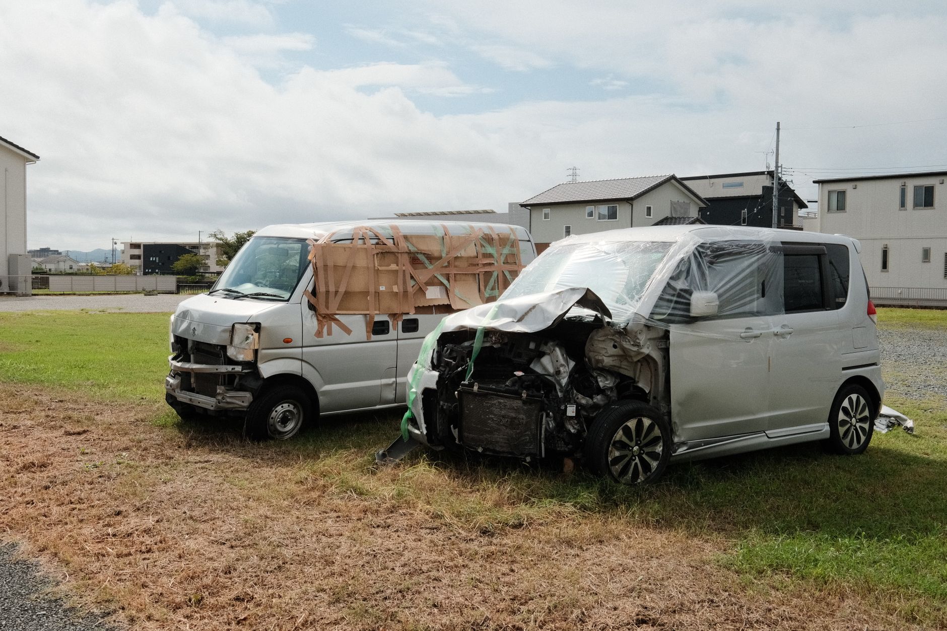 Dwa rozbite vany zaparkowane na trawiastym terenie w Japonii