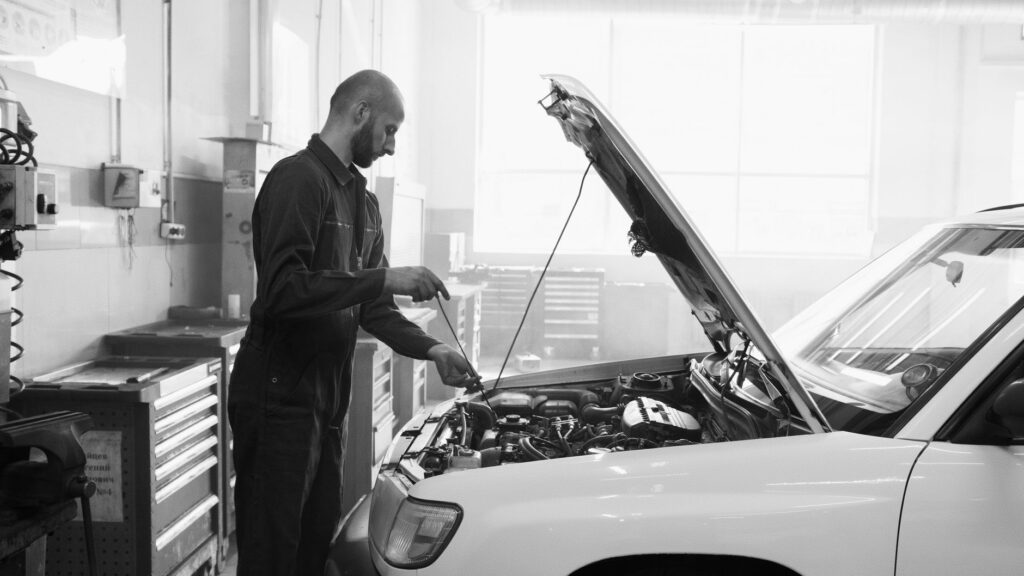 Mechanik w garażu wykonujący przegląd silnika samochodu